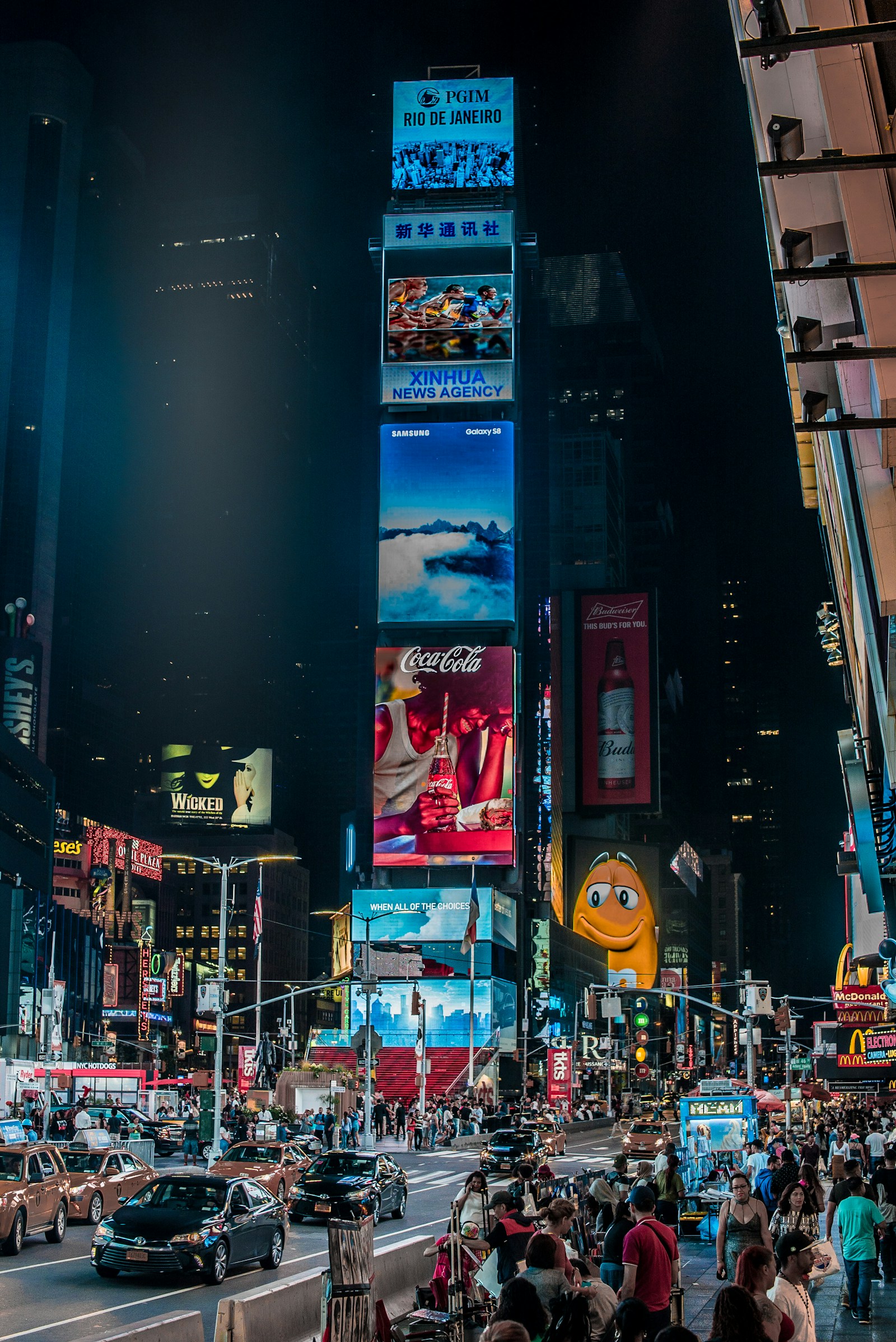 Pantalles publicitàries il·luminen Times Square de nit, entre edificis, taxis i vianants.